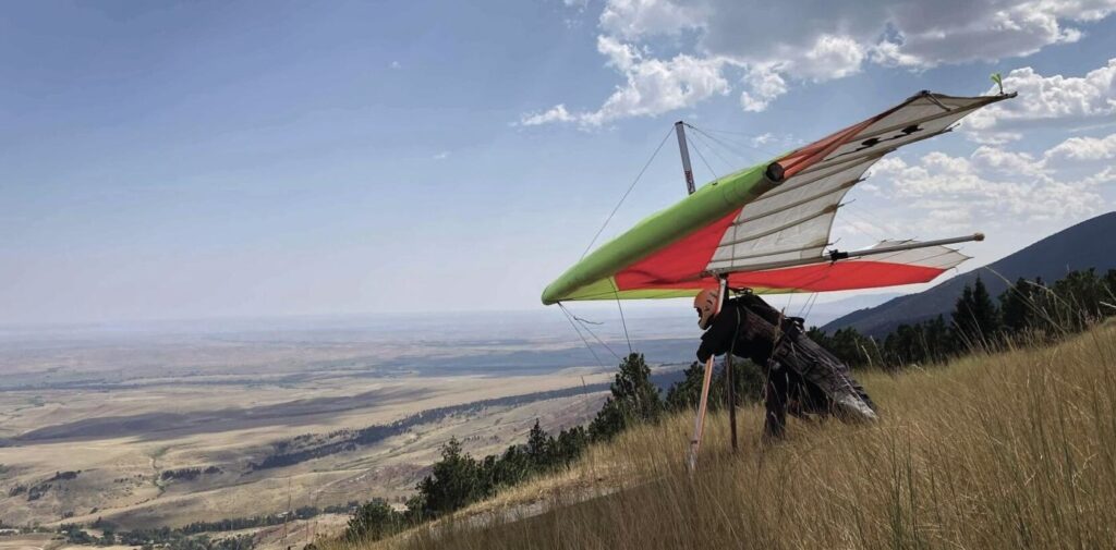 A man on a hang glider descends from the mountains