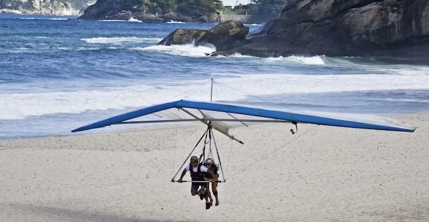 People fly on a hang glider over the seashore