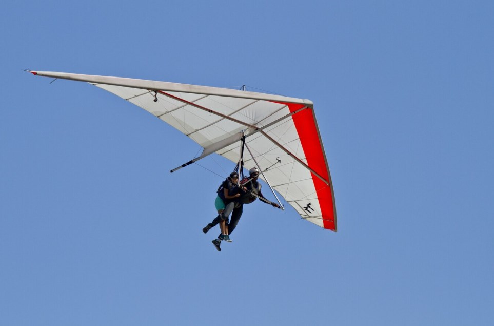 a person flying on a hang glider with an instructor