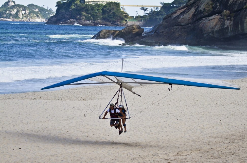 a couple flying on a hang-glider close to the ground