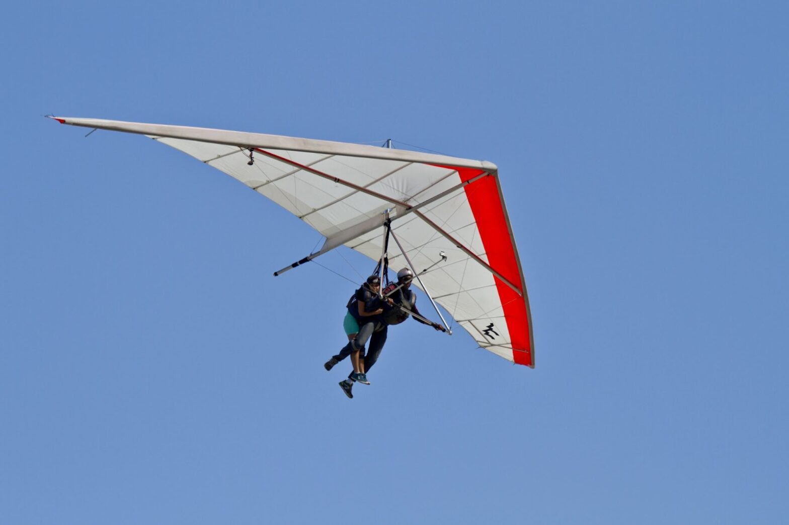 Human flying on a hang glider on a blue sky background