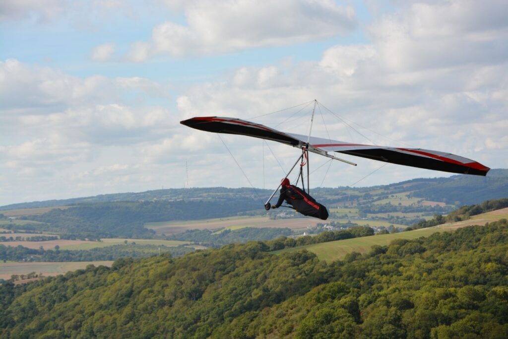 A man flies on a hang glider over the forests