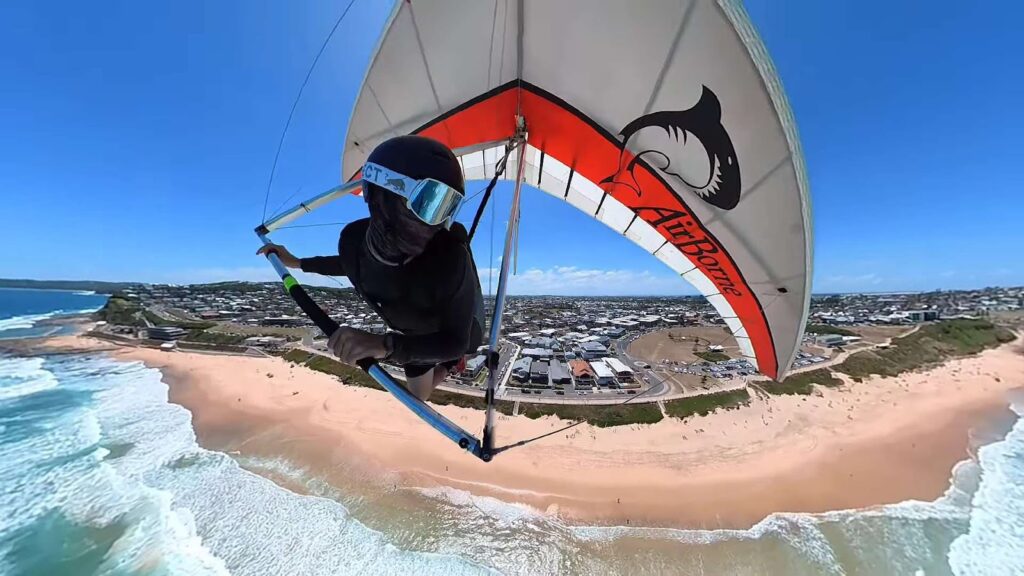 Human flying on a hang glide near sea