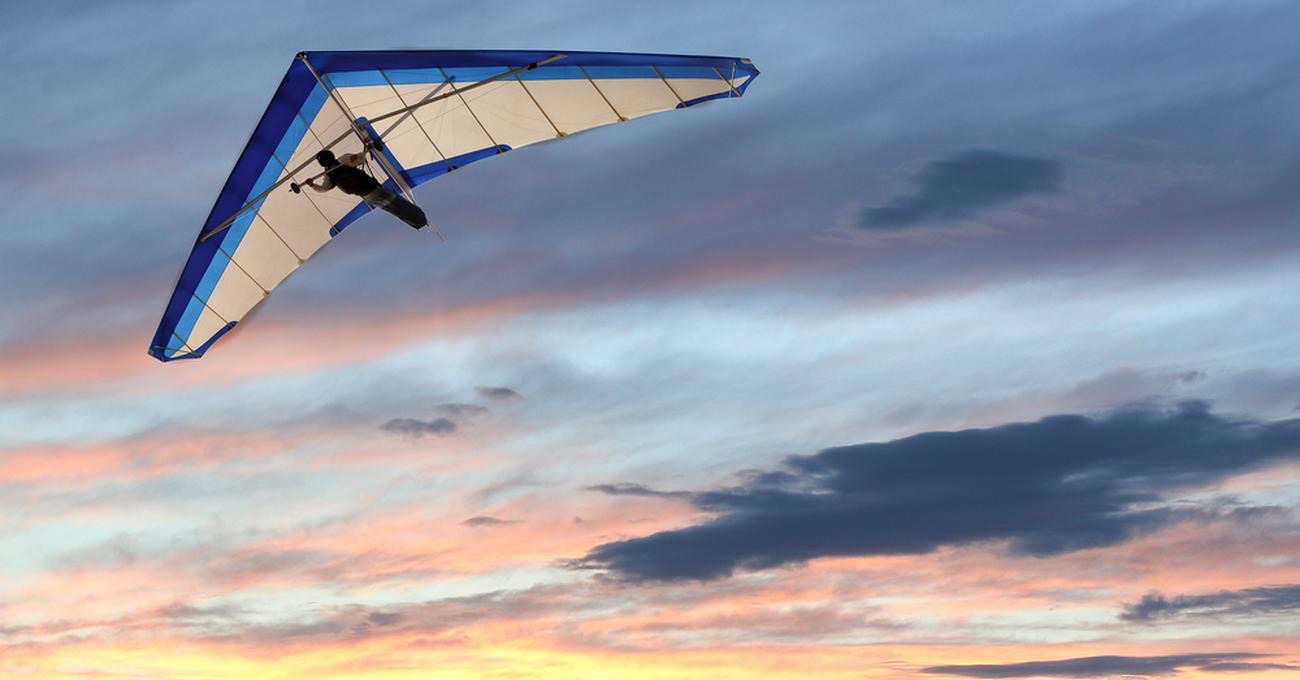 A man flies on a hang glider against the background of clouds