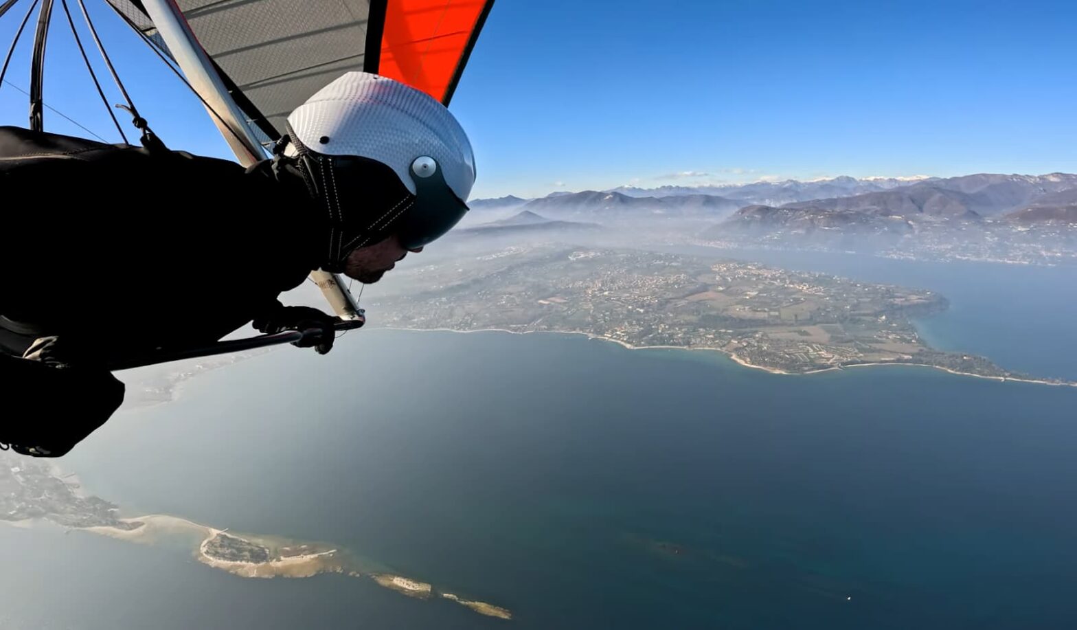Hang glider flying high above a coastline with mountain views
