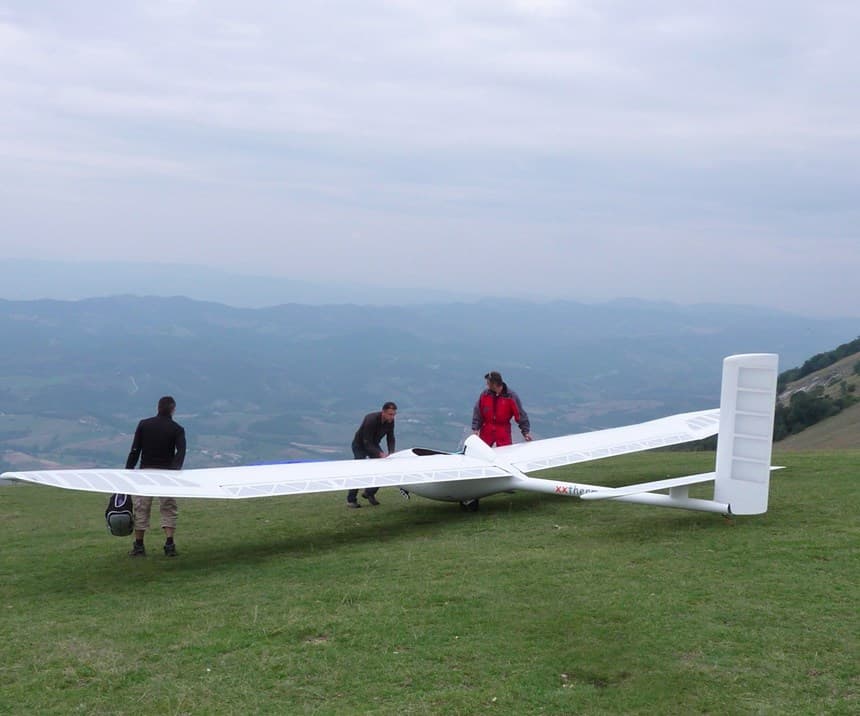 People standing near the wing of a white glider