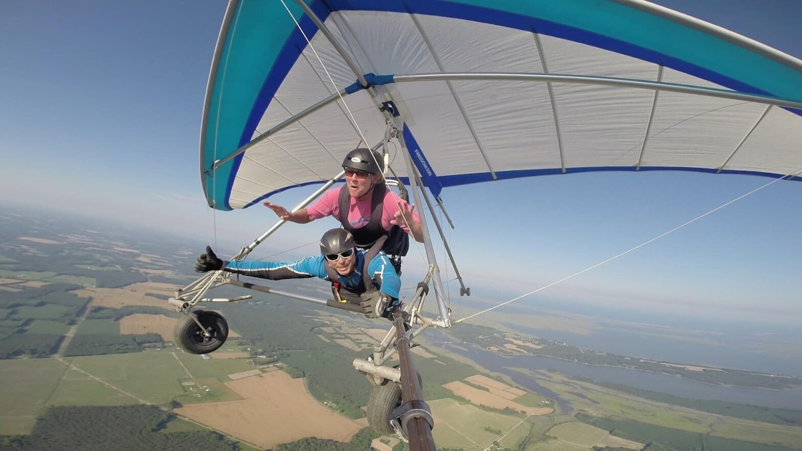 Two men flying on a hang glider and smiling