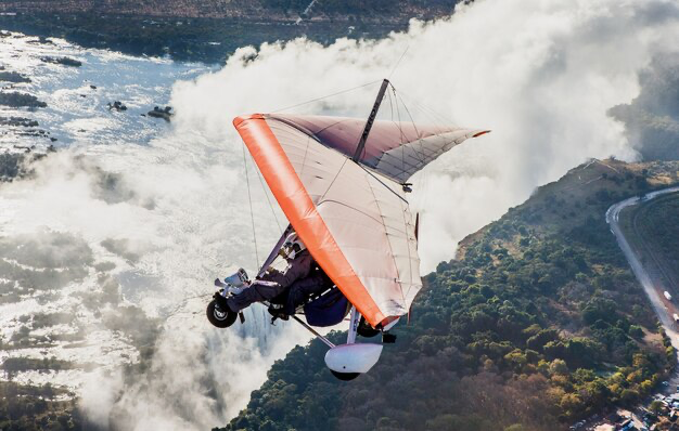 A man flies on a hang glider over the sea, view from the sea